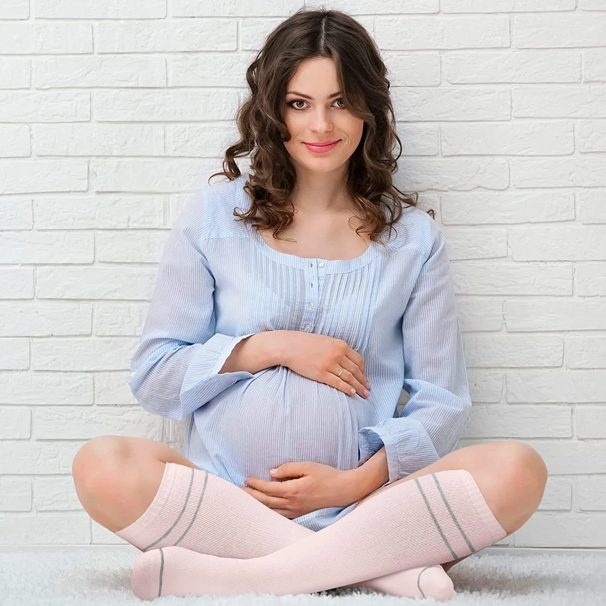 Pregnant woman sitting cross-legged in blush pink knee-high socks